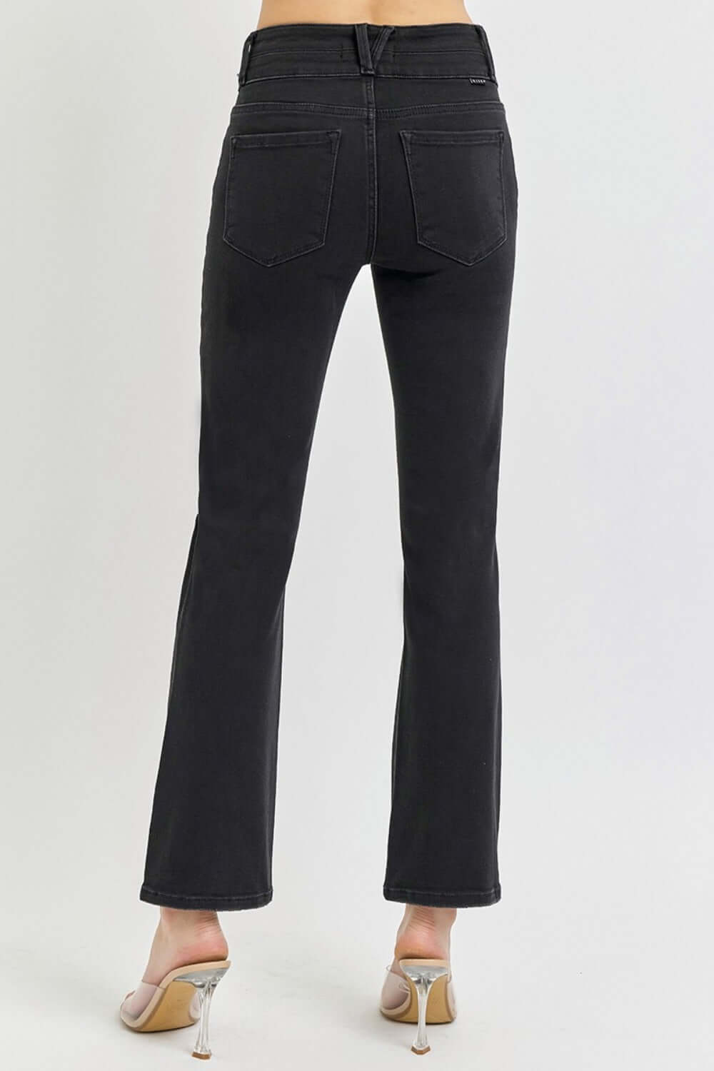 High-rise wide waistband ankle bootcut jeans in black, shown from the back, paired with heels for a modern, flattering look.