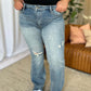 Woman wearing Judy Blue full size medium rise tummy control destroy flare jeans with distressed detailing, standing indoors.