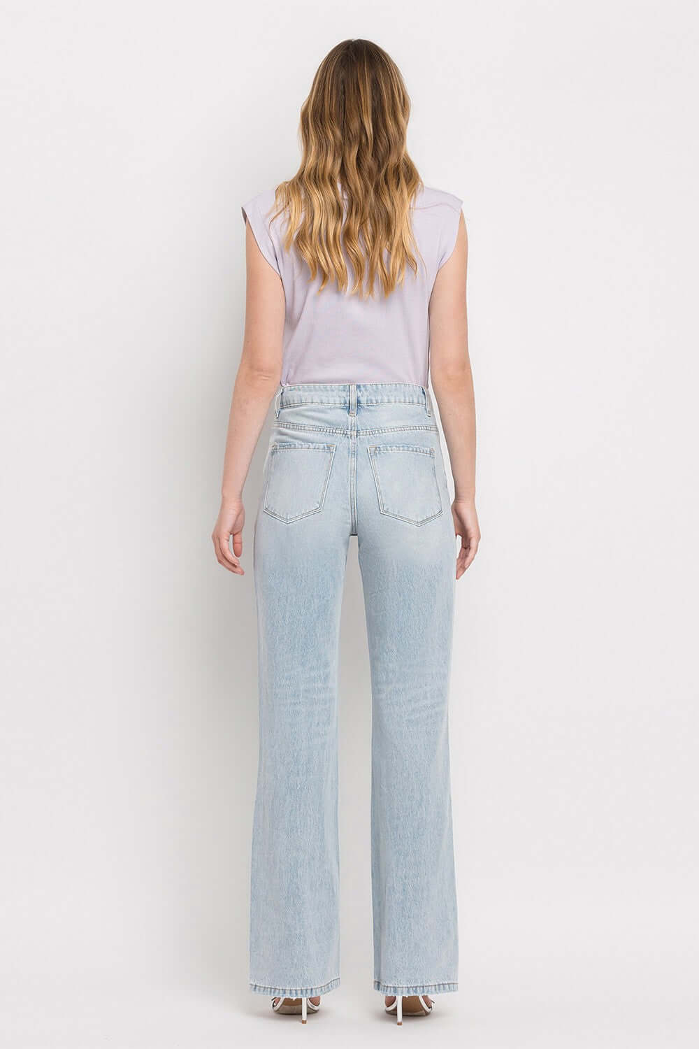 90's Vintage Super High Rise Flare Jeans in light wash denim worn by model facing back showcasing flared legs and high-rise waist