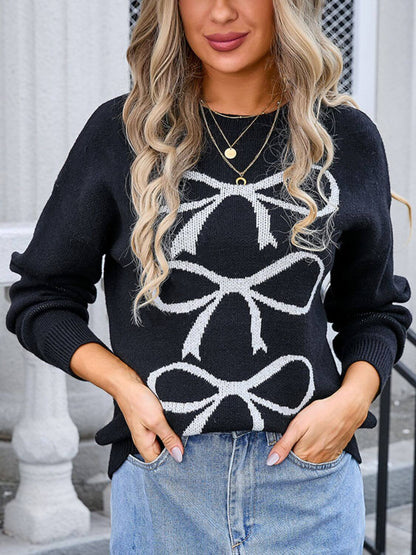 Woman wearing black round neck long sleeve sweater with white bow graphic design, paired with light-wash jeans and gold necklaces