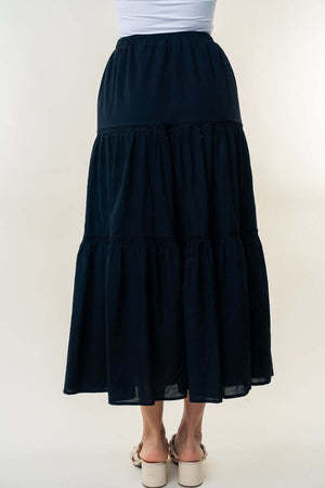 Woman wearing high waisted tiered maxi skirt with a flowy and feminine silhouette in black.