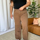 Woman wearing RFM High Rise Garment Dye Wide Leg Jeans with black top, standing in a stylish living room.