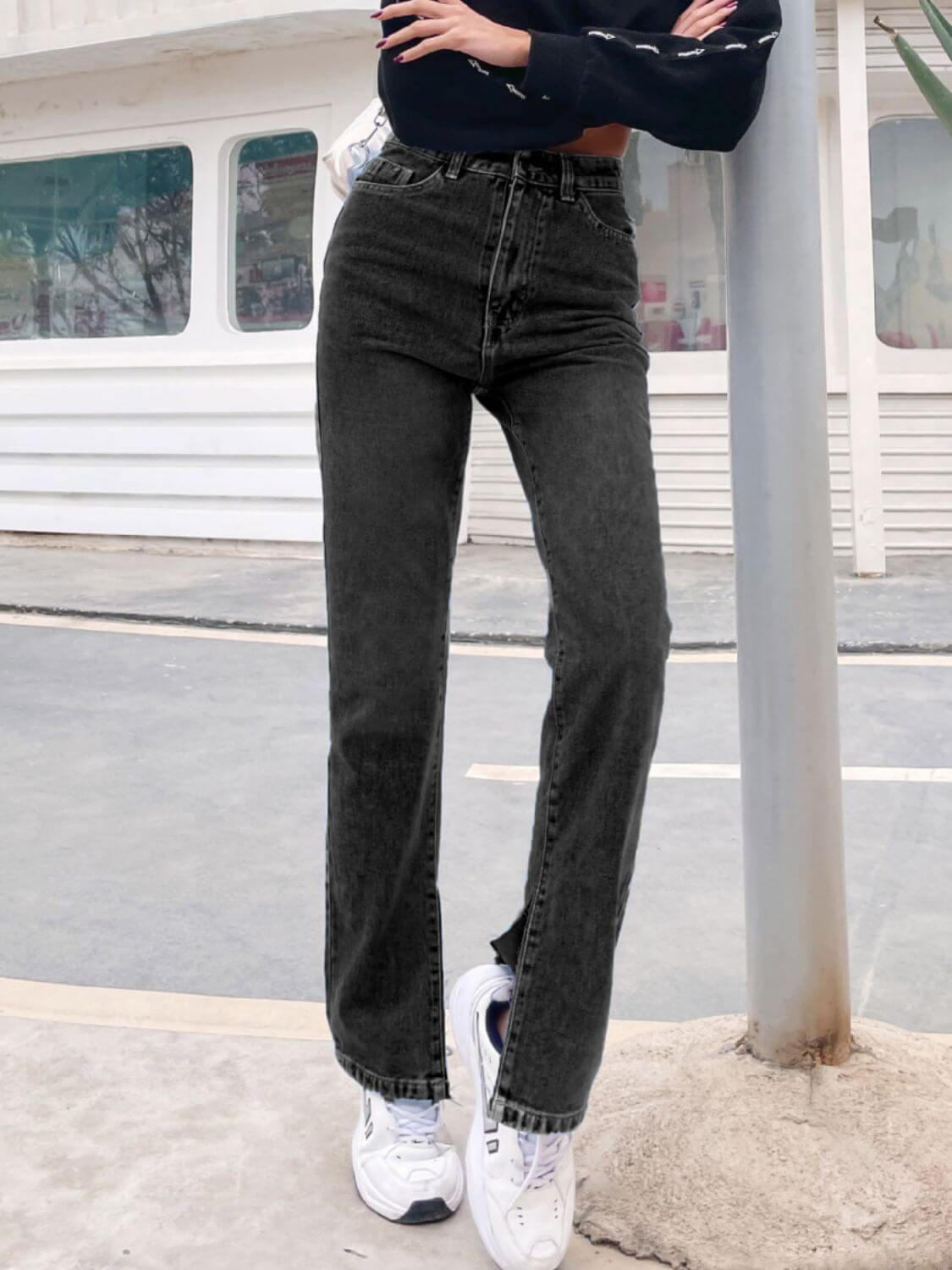 Bella Road Side Slit High Waist Jeans with Pockets in black, worn by model standing outdoors, showcasing stylish side slits and flattering fit.