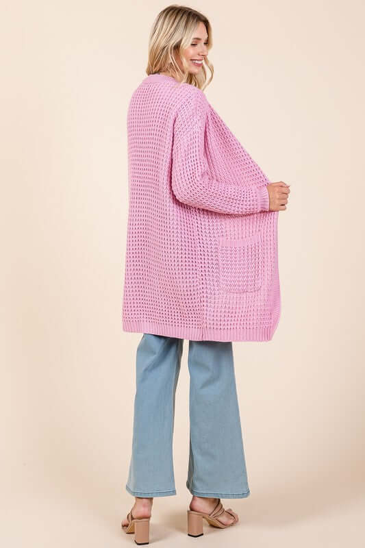 Stylish pink longline cardigan with open front and long sleeves, paired with light blue jeans for a chic look.