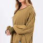 Woman wearing an oversized mineral wash side slit sweatshirt with a scoop neck and exposed seams, showcasing a comfortable and stylish look.