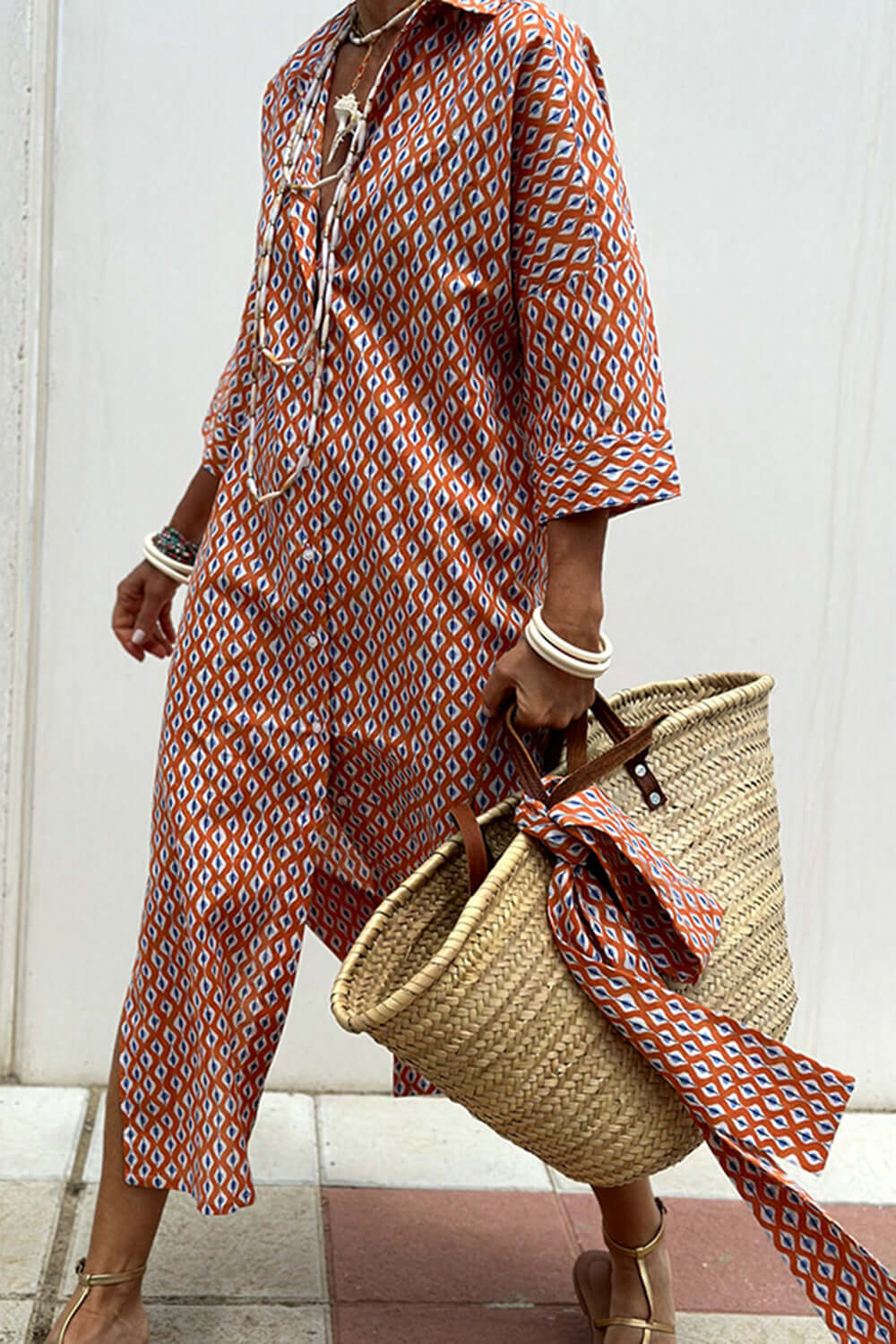 Bella Road Tied Button Up Three-Quarter Sleeve Dress in patterned fabric, styled with a straw tote bag and sandals for a chic, casual look.