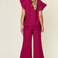 Woman wearing fuchsia texture ruffle short sleeve top and drawstring wide leg pants set, viewed from the back.