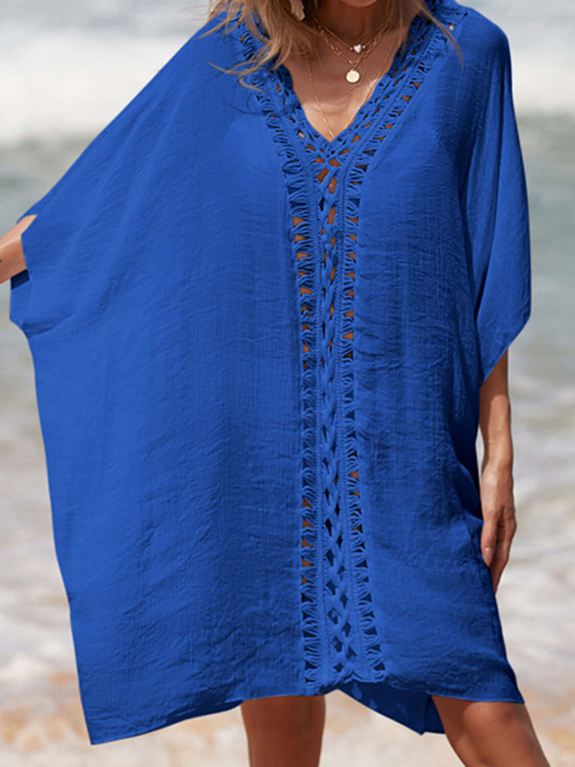 Woman wearing a blue cutout V-neck three-quarter sleeve cover-up on the beach.