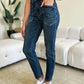 Woman in High Waist Skinny Judy Blue Jeans with white sneakers standing in a modern living room.