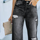 Woman wearing distressed straight leg jeans with a casual top and holding a clutch bag.