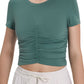 Woman wearing a stylish green ruched round neck short sleeve active t-shirt, perfect for workouts and casual wear.