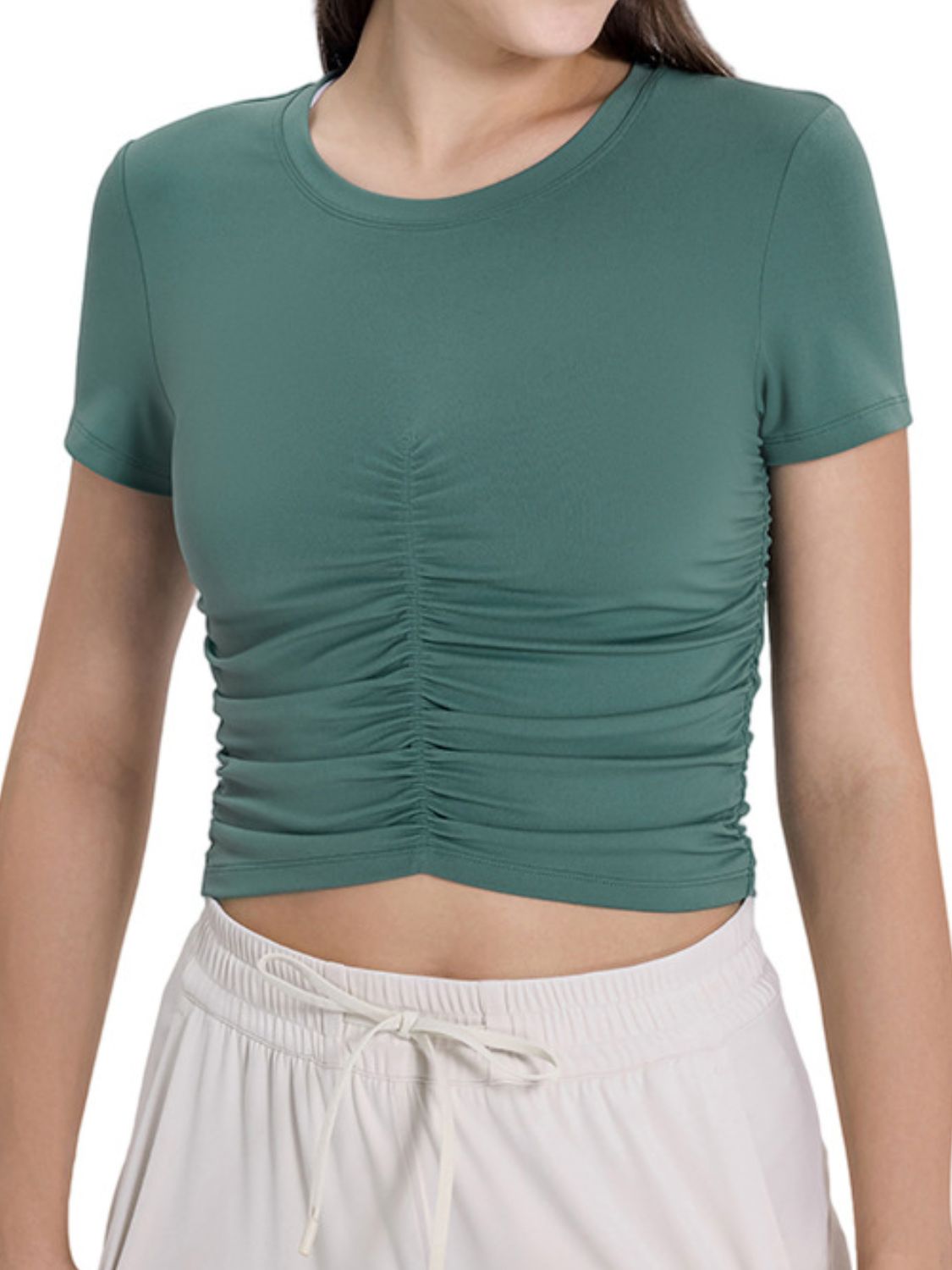 Woman wearing a stylish green ruched round neck short sleeve active t-shirt, perfect for workouts and casual wear.