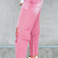 Woman wearing pink distressed raw hem jeans with pockets and white ankle boots.