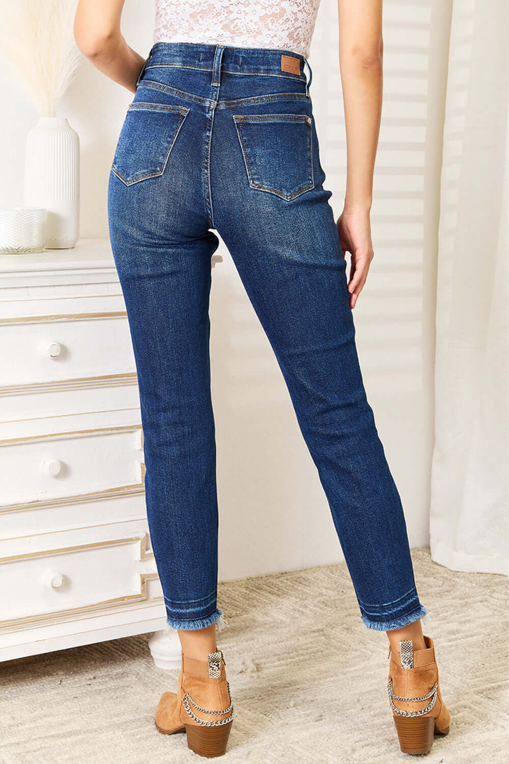 Woman wearing high waist released hem slit Judy Blue Jeans in deep indigo wash, back view showing slim silhouette and sophisticated design.