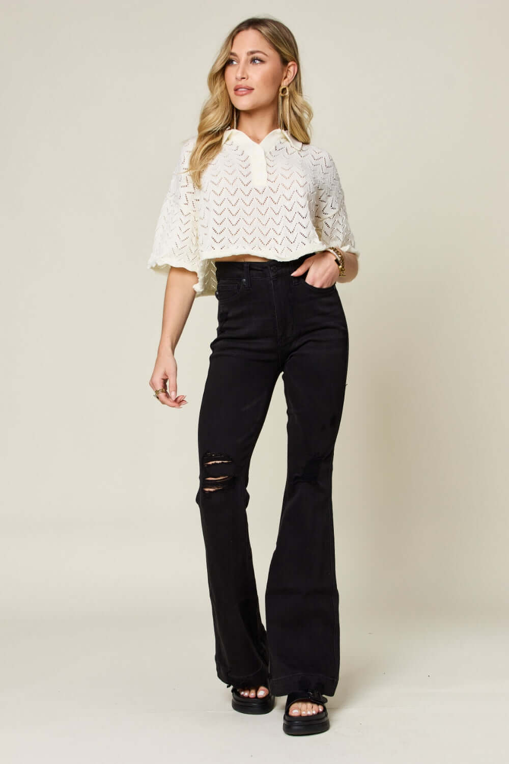 Woman wearing high waist distressed flare jeans in full size from Judy Blue Jeans with a white textured top, showcasing a retro-inspired fashion look.