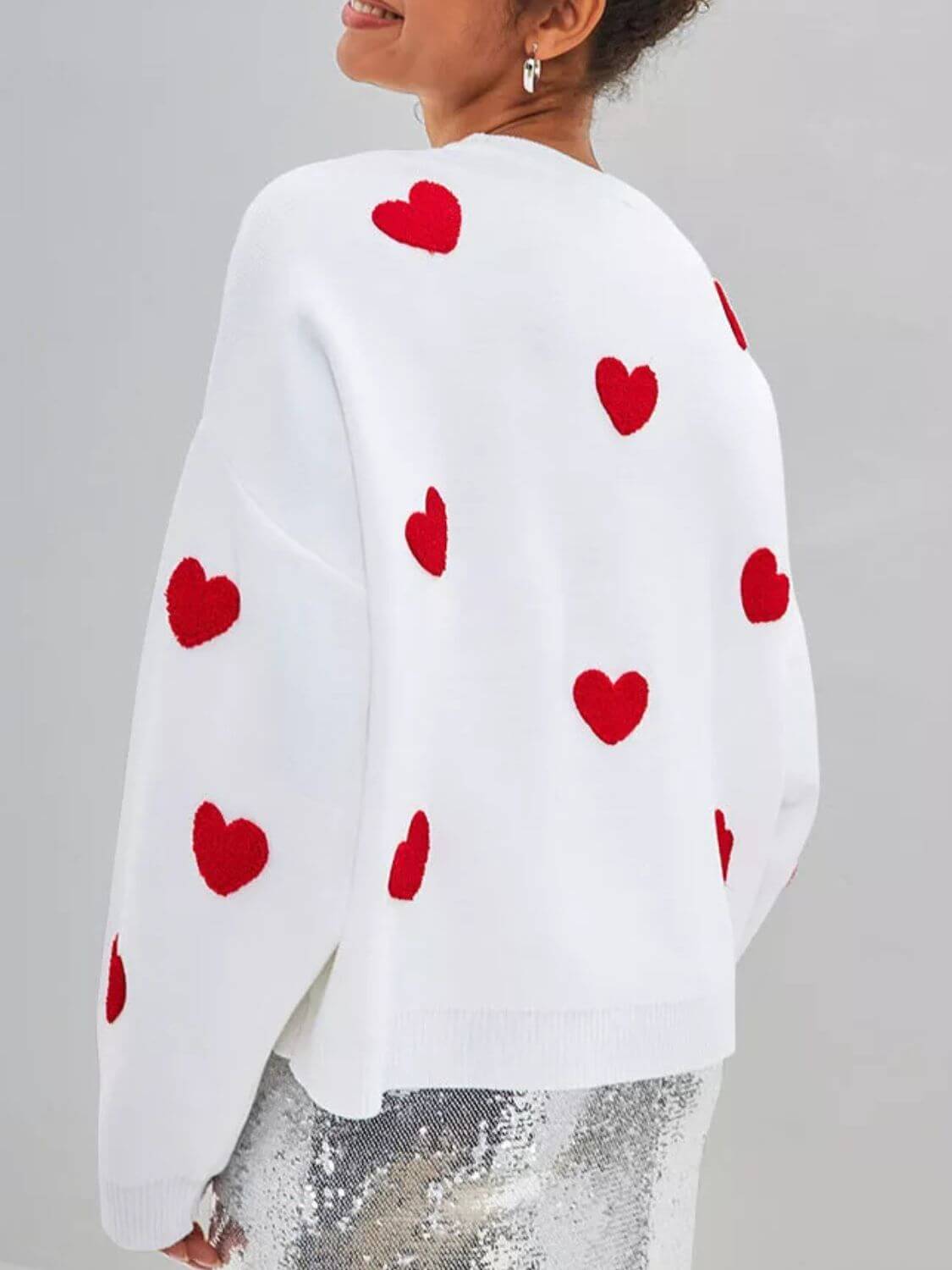 Woman wearing Bella Road Heart Round Neck Dropped Shoulder Sweater with red heart details from back.