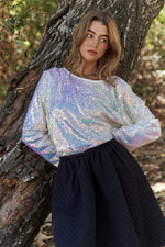 Shimmery sequin long sleeve crop t-shirt styled with a black skirt, perfect for adding glam to any outfit.