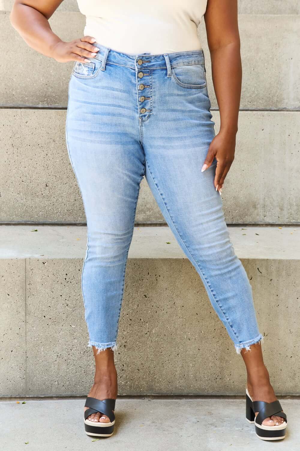 Woman wearing Judy Blue Button Fly Raw Hem Jeans with a casual look. Featuring pockets, moderate stretch, and comfortable material.