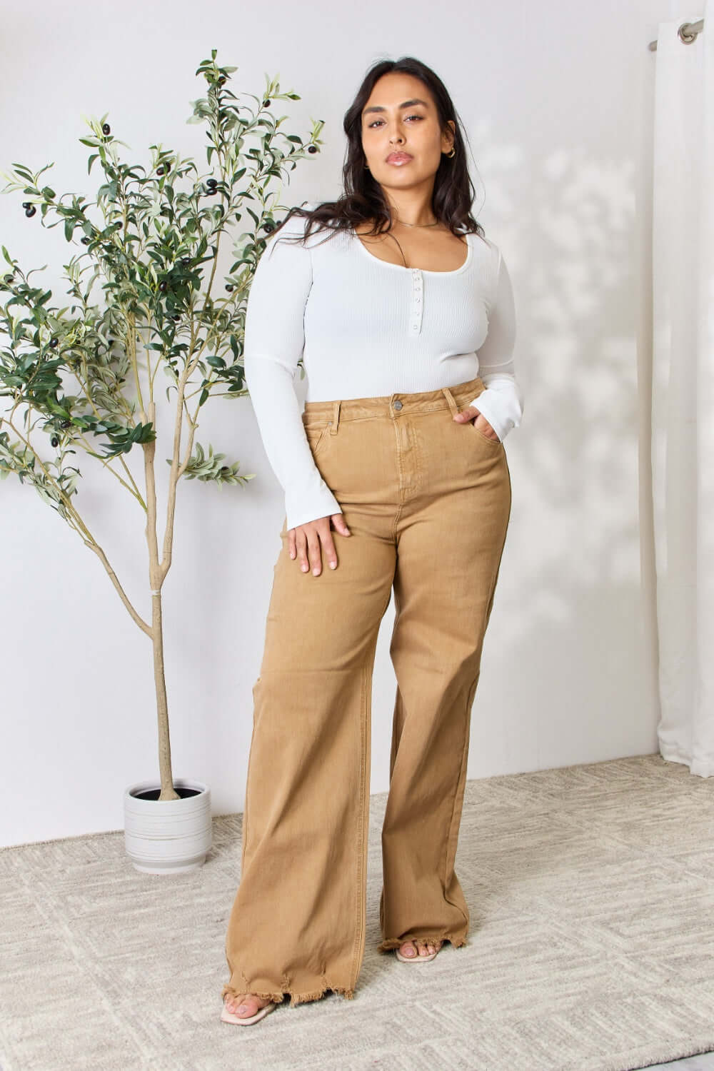 Model wearing Risen Fringe Hem Wide Leg Jeans in a high-waisted fit with a trendy wide-leg design, paired with a white top.