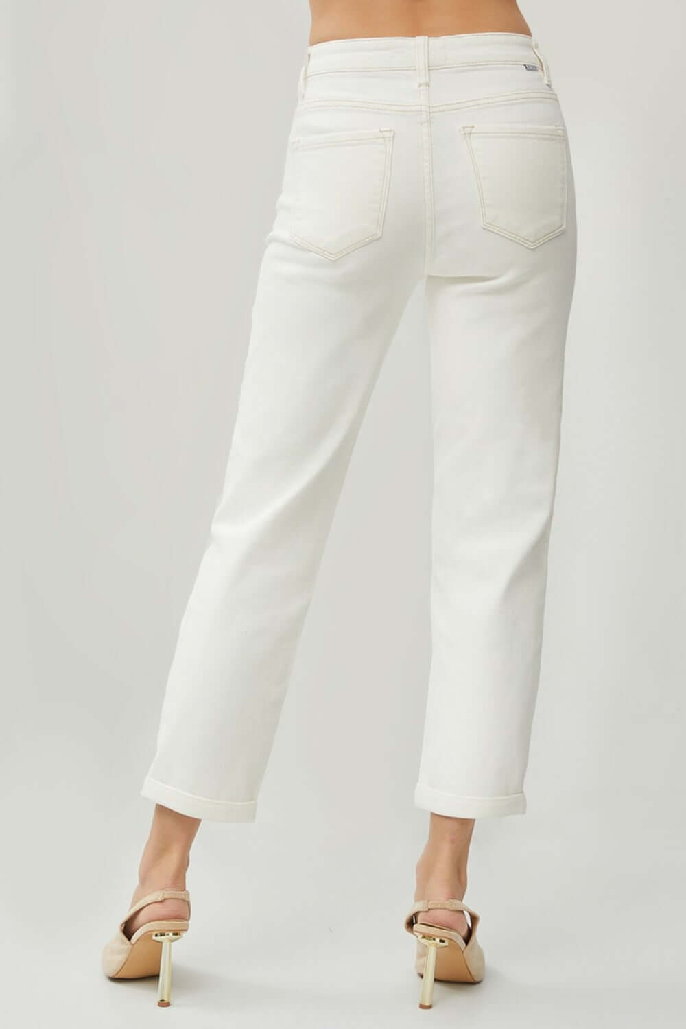 Woman wearing RISEN Full Size High Waist Rolled Hem Straight Jeans in white, showcasing back view with rolled hems and high waist design.