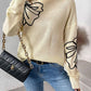 Woman wearing Perfee Mock Neck Dropped Shoulder Long Sleeve Sweater in cream with floral design and black quilted handbag