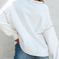 Woman wearing Bella Road MARDI GRAS Round Neck Long Sleeve Sweatshirt, showing cozy back design and relaxed fit with denim jeans.