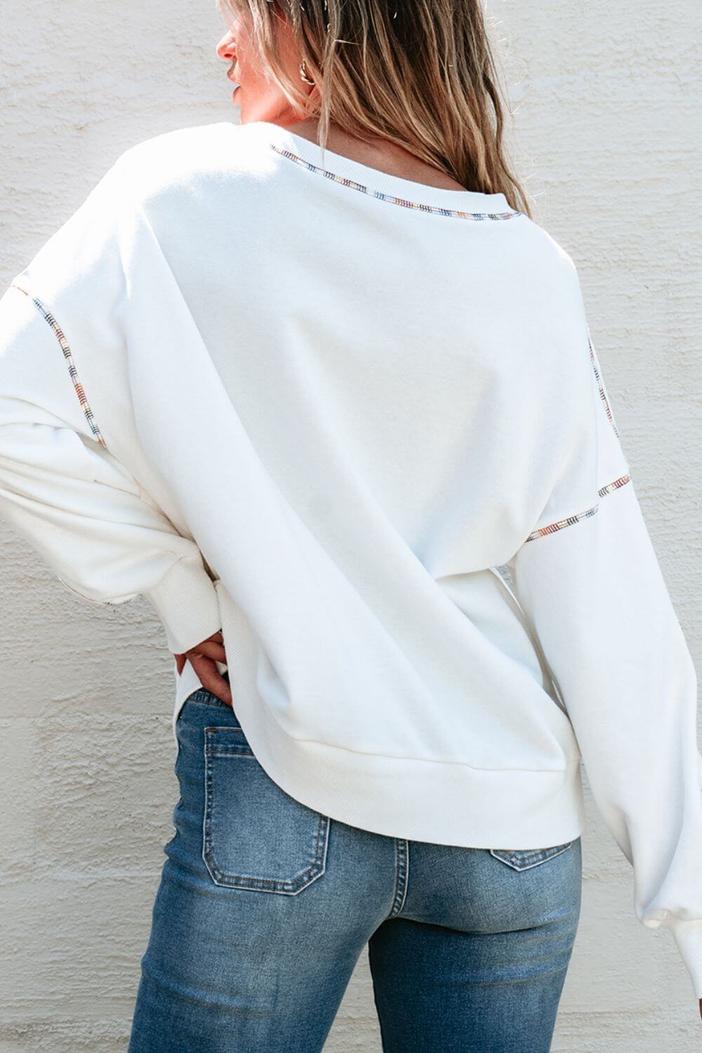 Woman wearing Bella Road MARDI GRAS Round Neck Long Sleeve Sweatshirt, showing cozy back design and relaxed fit with denim jeans.