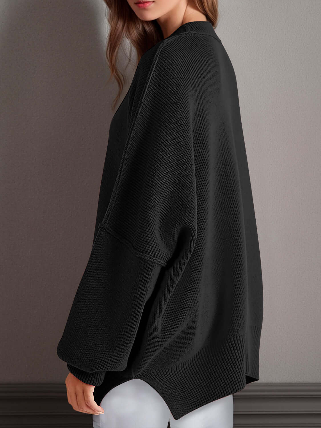 Woman wearing a black Double Take Side Slit Round Neck Long Sleeve Sweater with hand by her side