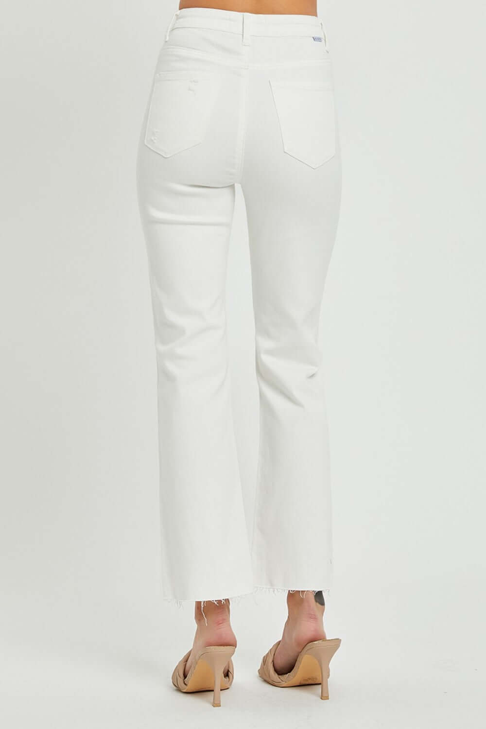 Woman wearing Risen Jeans high rise button fly straight ankle jeans in white, showing back view with stylish minimal design.