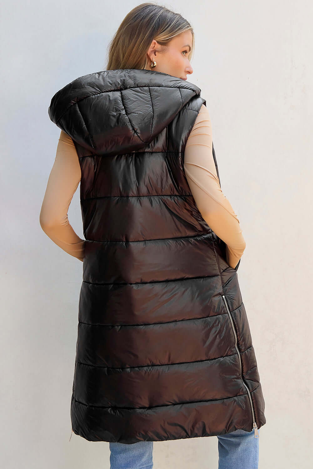 Woman wearing Bella Road Longline Hooded Sleeveless Puffer Vest, perfect for layering and outdoor adventures, side view.