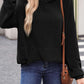 Woman wearing a black textured kangaroo pocket long sleeve hoodie, paired with blue jeans and a brown crossbody bag.