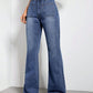 High waist bootcut jeans with pockets in blue denim, buttoned closure, displayed on model with white top and sandals.