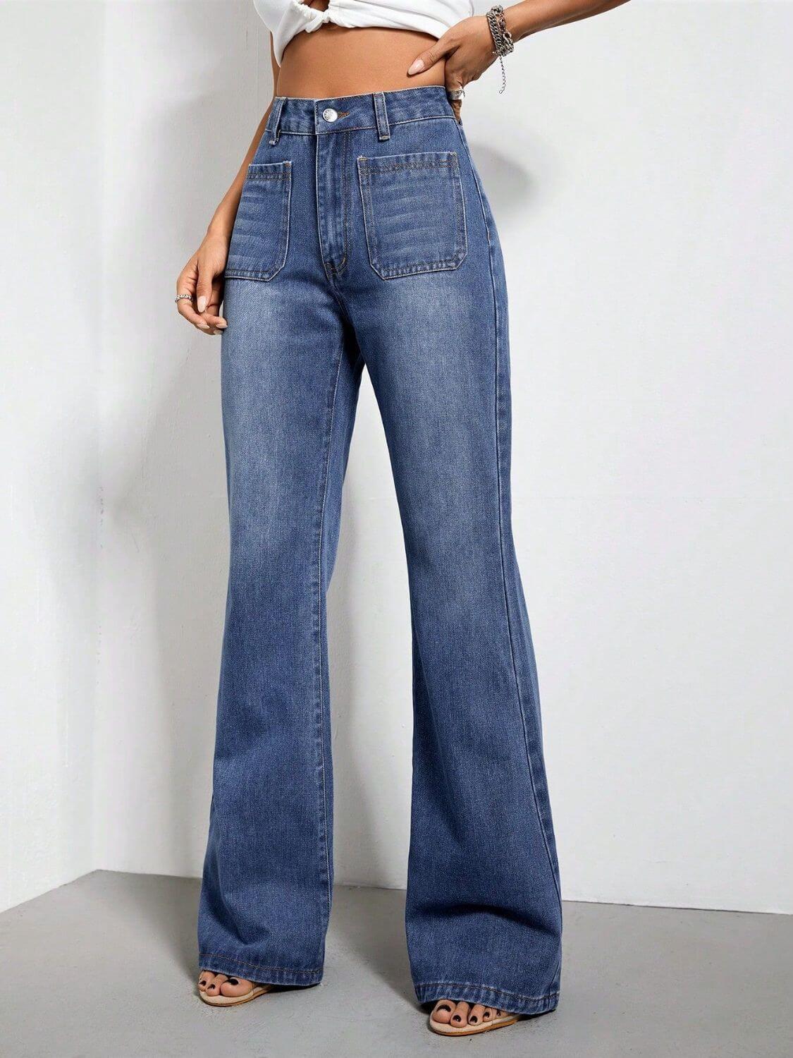 High waist bootcut jeans with pockets in blue denim, buttoned closure, displayed on model with white top and sandals.