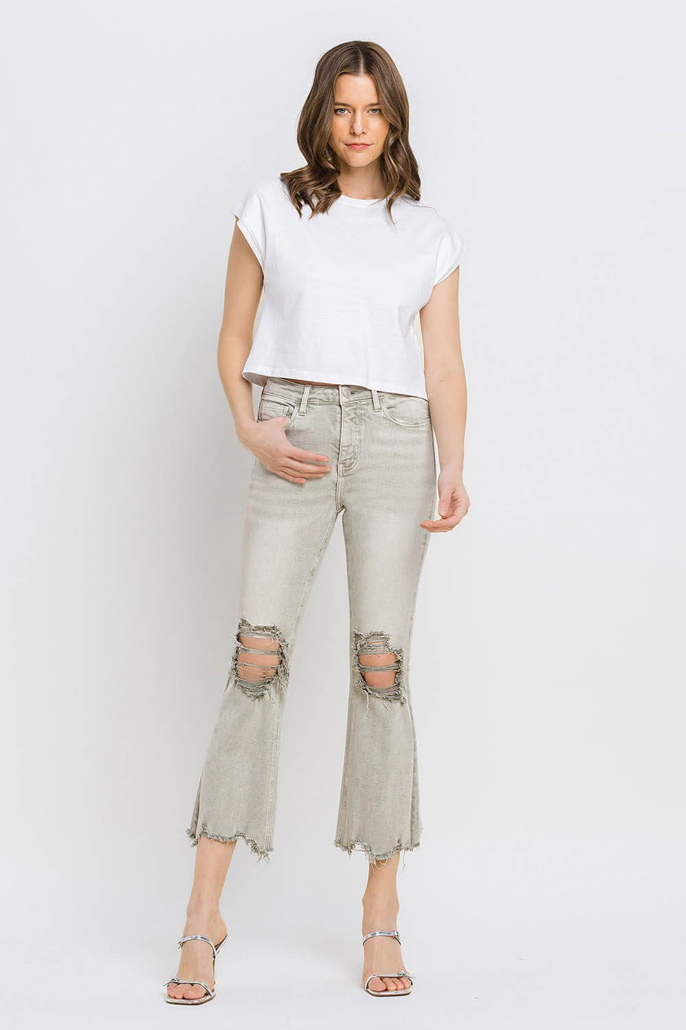 Woman wearing Lovervet distressed raw hem cropped flare jeans with white tee and sandals.