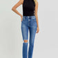 Woman wearing RISEN high-rise ankle skinny knee distressed jeans with black sleeveless top and black sandals