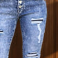 Close-up of distressed button-fly bootcut jeans with pockets, featuring a trendy petite fit and stylish rips.