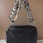 Stylish black Cassette Woven Crossbody Bag with a trendy leopard print strap, perfect for hands-free convenience.