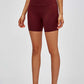 High-waisted burgundy training shorts with a 5-inch inseam, perfect for workouts and lounging, paired with a crop top and sneakers.