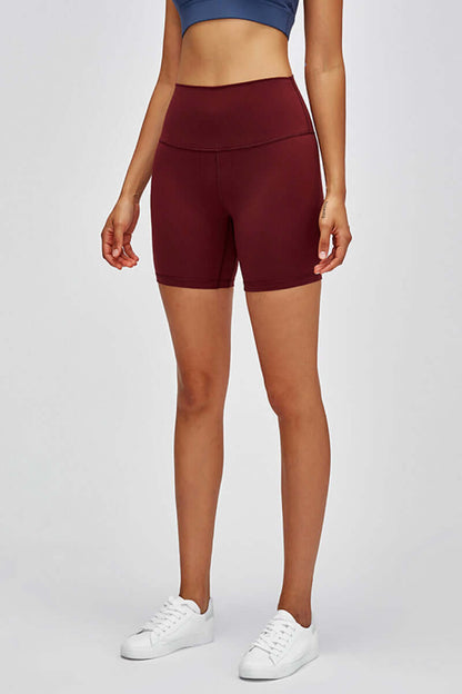 High-waisted burgundy training shorts with a 5-inch inseam, perfect for workouts and lounging, paired with a crop top and sneakers.