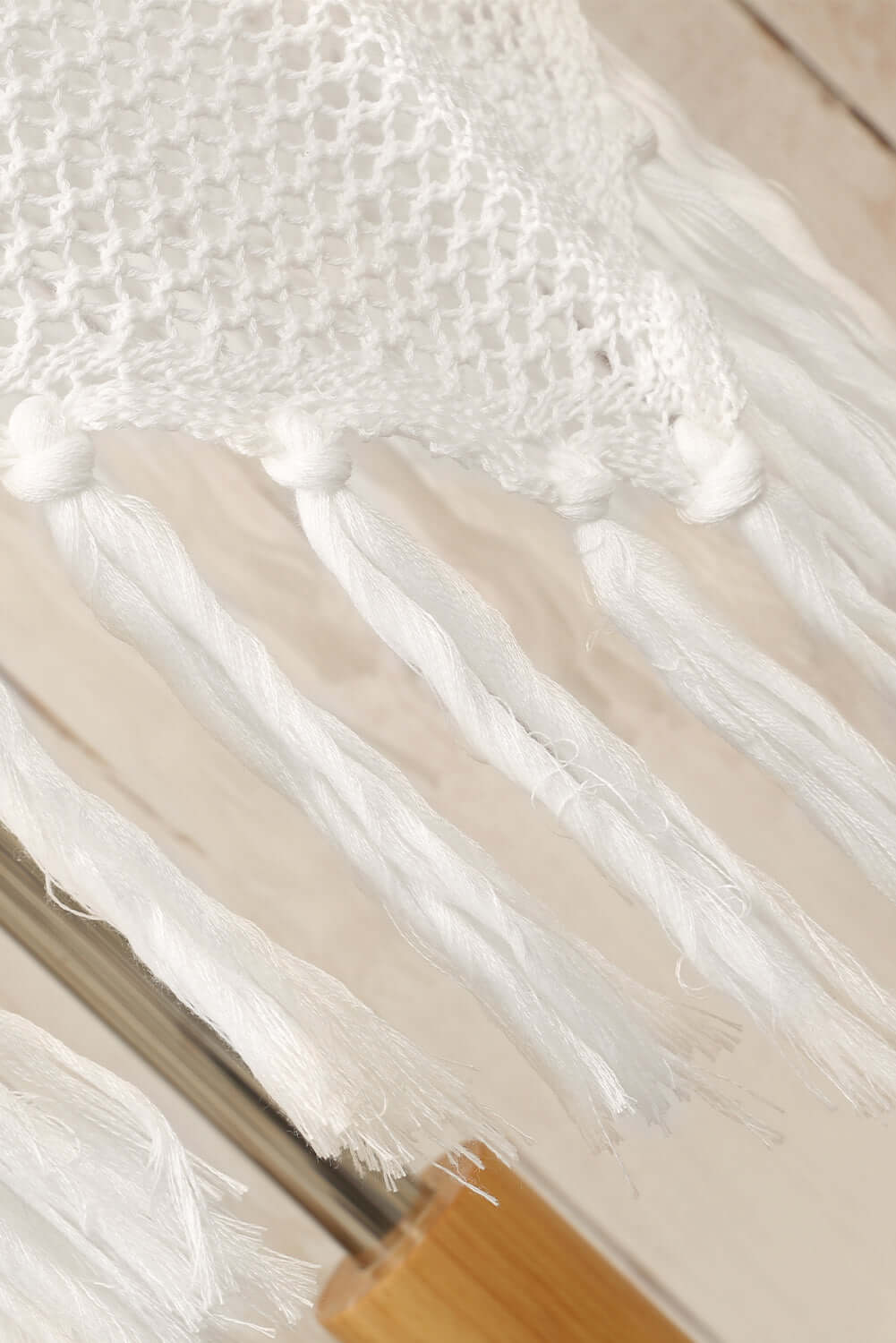 Close-up of white tassel details on the openwork spaghetti strap cover up dress, highlighting its intricate design and craftsmanship.