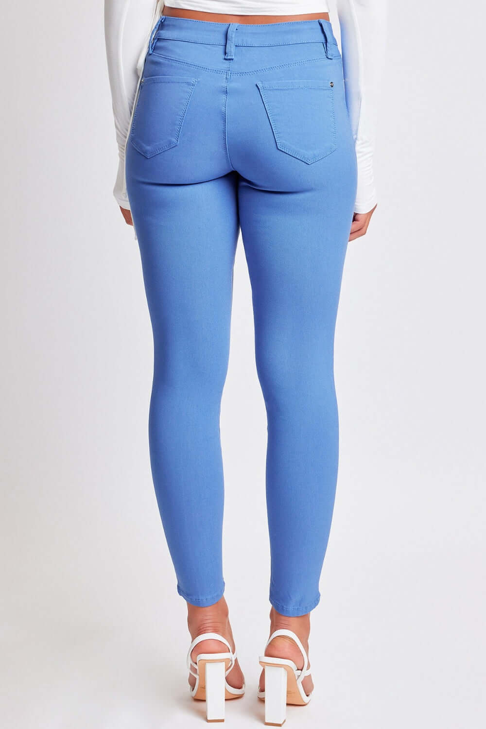 Woman wearing YMI Jeans Hyperstretch Mid-Rise Skinny Pants in vibrant blue, showcasing a flattering back view.