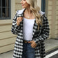 Woman wearing Bella Road Drawstring Plaid Long Sleeve Hooded Jacket in black and white with jeans, standing outdoors.