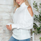 Woman wearing Bella Road Cable-Knit Turtleneck Cold Shoulder Sweater in white, showcasing cozy style with trendy cut-out shoulders.