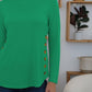 Woman wearing green FAM-FAM Round Neck Long Sleeve T-Shirt with decorative buttons, perfect for a fun and stylish casual look.