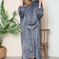 Cozy woman in a hooded grey midi lounge dress with pockets, perfect for fall lounging, paired with fluffy slippers.