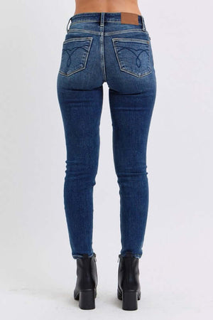 Back view of Judy Blue mid-rise skinny jeans featuring sleek pockets and a flattering fit, styled with ankle boots.