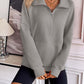 Woman wearing Ivy Lane Half Zip Raglan Sleeve Sweatshirt in gray with pocket, styled with black shorts, standing in a modern interior.