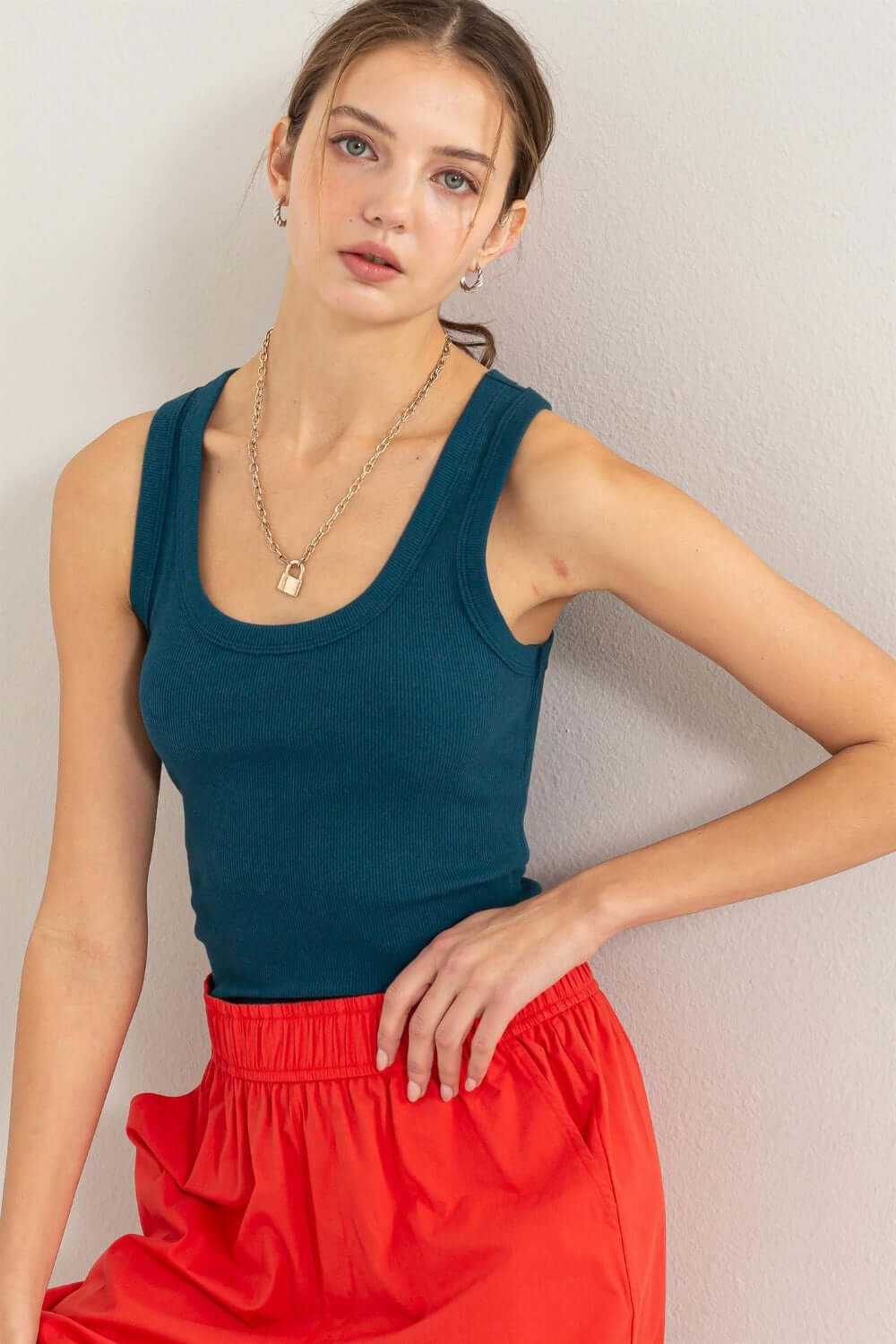 Woman wearing Ribbed Scoop Neck Racerback Tank in blue, paired with red pants, showcasing a comfortable and stylish look.