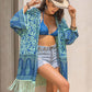 Stylish woman in a blue fringe cover-up over bikini, wearing a hat and shorts, perfect for beach outings.