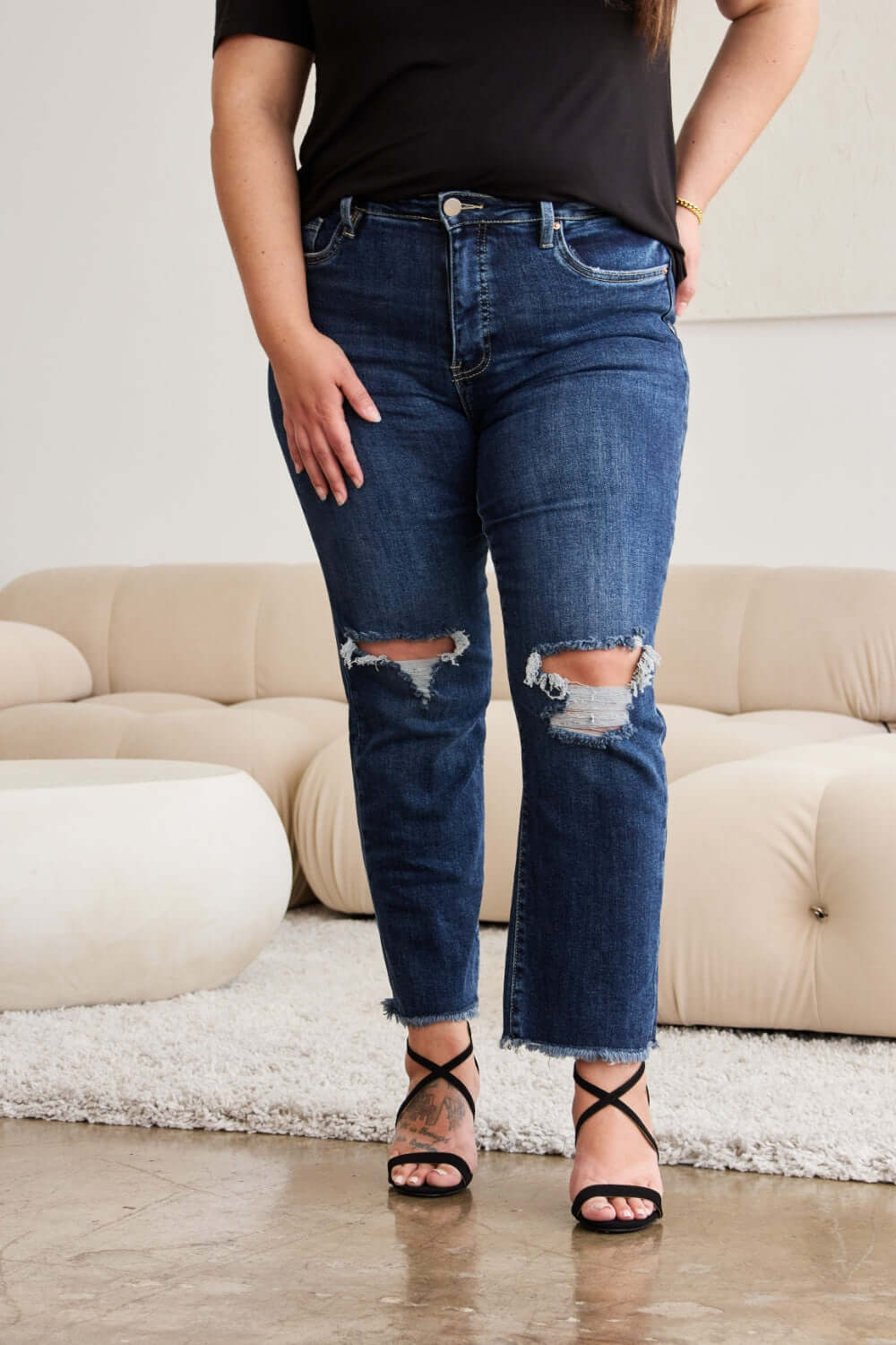 Woman wearing RFM Jeans Crop Dylan Full Size Tummy Control Distressed High Waist Raw Hem Jeans in a stylish outfit